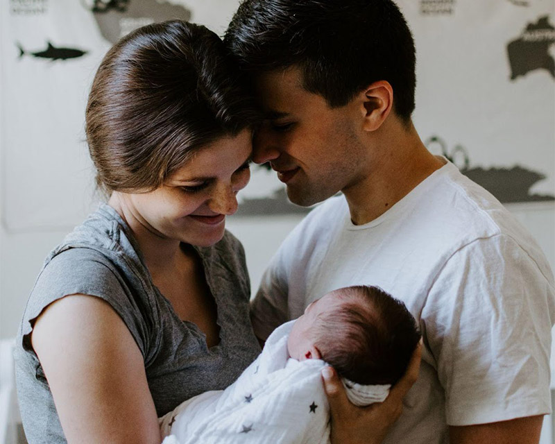 New parents holding their baby and looking at the baby's face.