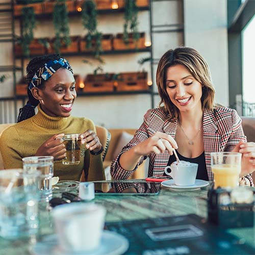Two women talking together at a coffee shop.